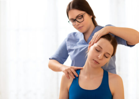 Female Physiotherapist Or A Chiropractor Adjusting Patients Neck. Physiotherapy, Rehabilitation Concept. White Background Front View With Copy Space.